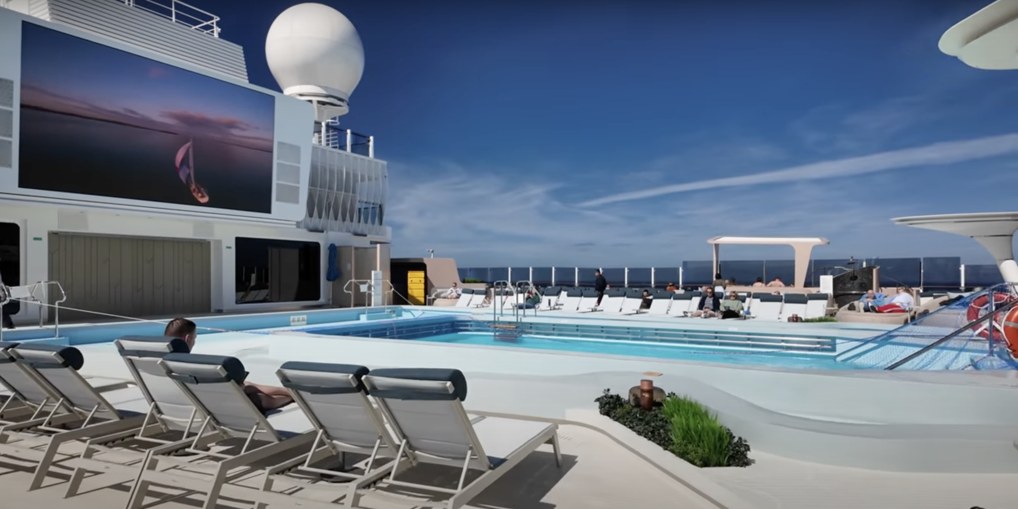 Norwegian Aqua cruise ship pool deck with modern design, loungers, large screen, and visible safety concerns related to slippery flooring.